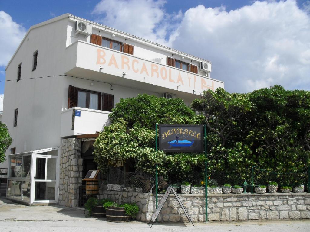 un edificio blanco con un cartel delante en Apartments Barcarola, en Pag