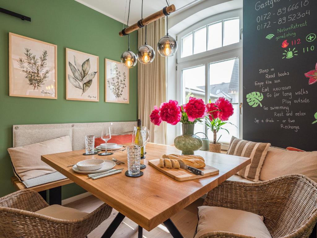 a dining room with a wooden table with flowers on it at NEU Nature Retreat - Traumhafte Wohnung mit privater Sauna - 100m vom Strand in Rerik