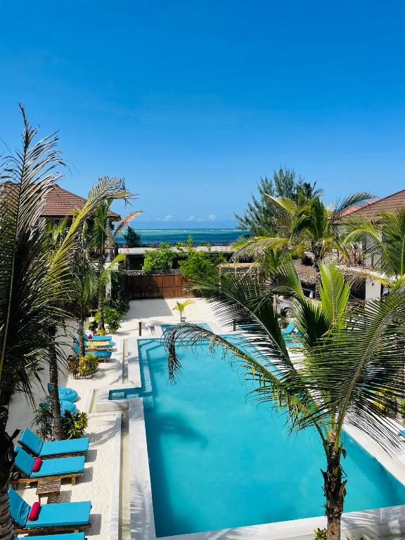 a view of the pool at the resort with palm trees at Sand Beach Boutique in Bwejuu