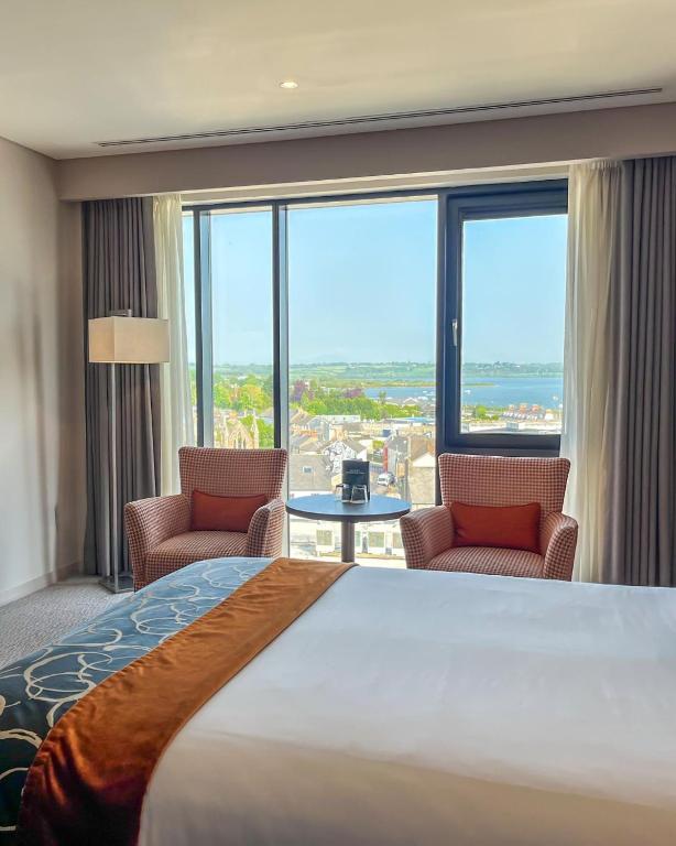 a hotel room with a large bed and two chairs at Whites of Wexford in Wexford