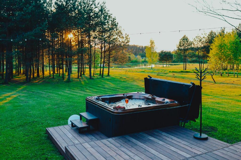 a hot tub sitting on a deck in a field at Baldones dabas retrīts - Exclusive holiday house near Riga jacuzzi sauna extra cost in Pulkarne