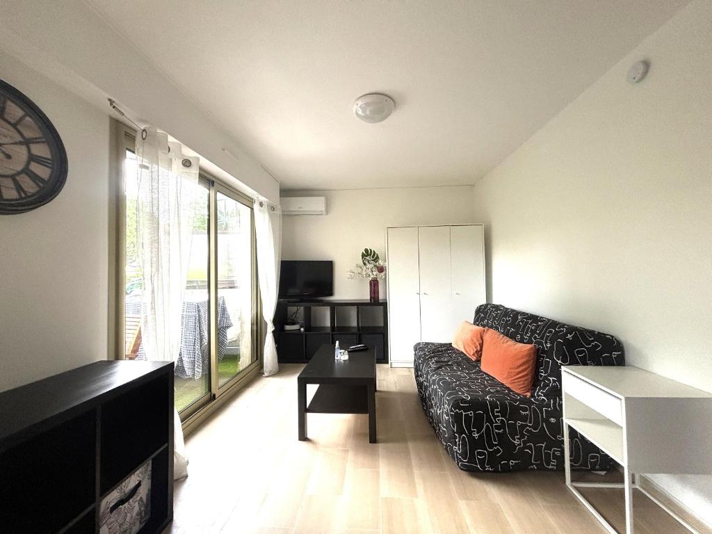 a living room with a couch and a clock on the wall at Studio bord de mer in Fréjus