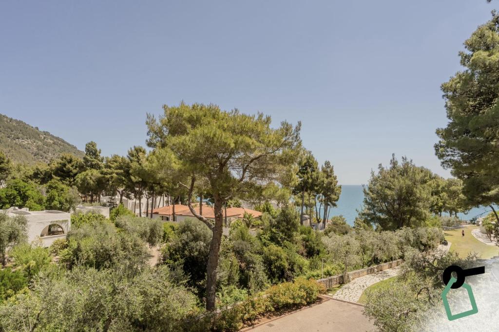 a view of a park with trees and the ocean at HOTIDAY Room Collection - Mattinata Faraglioni in Mattinata
