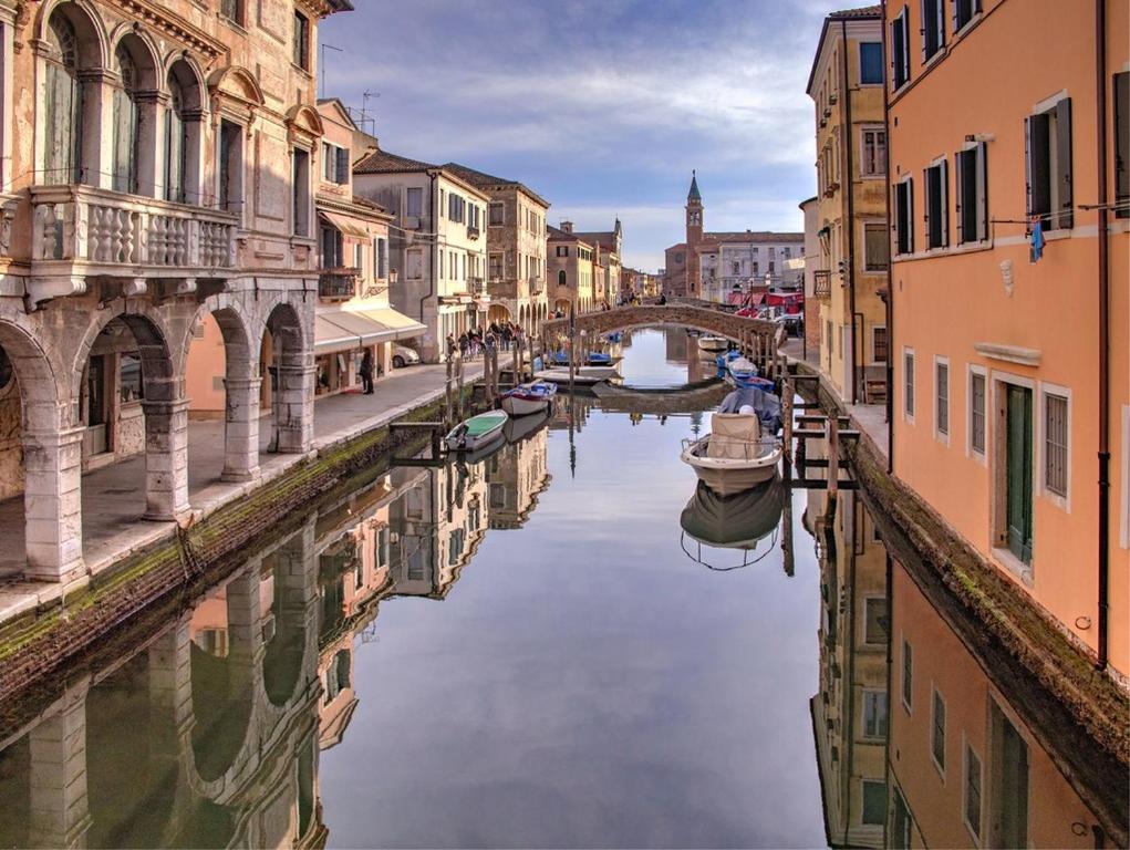 a canal in a city with buildings and boats at Blu House in Chioggia