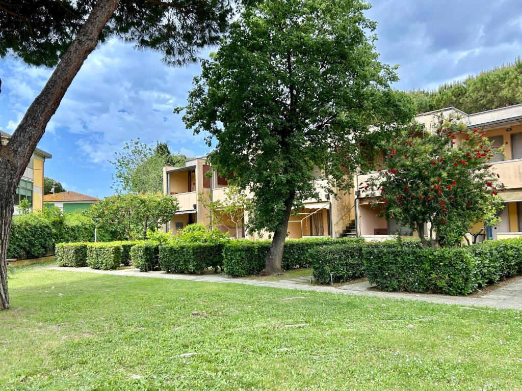 an apartment building with trees and bushes in a yard at Bilocali del Sole in Marina di Bibbona