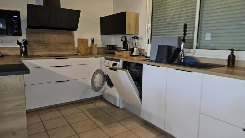 La cuisine est équipée de placards blancs et d'un lave-vaisselle. dans l'établissement Villa d elna, à Elne