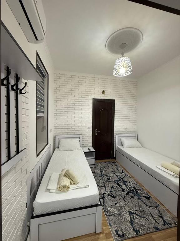 a white room with two beds and a rug at SumayShakh Guest House in Bukhara