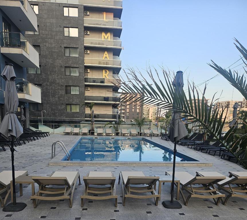 a swimming pool with chairs and a building at Mira apartament by Alezzi n10 in Mamaia Nord
