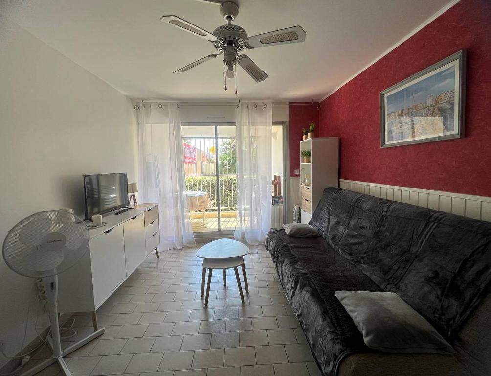 un salon avec un canapé et un ventilateur de plafond dans l'établissement DEUX PIECES EN REZ DE CHAUSSEE A DEUX PAS DE LA PLAGE DU MOLE, au Cap d'Agde