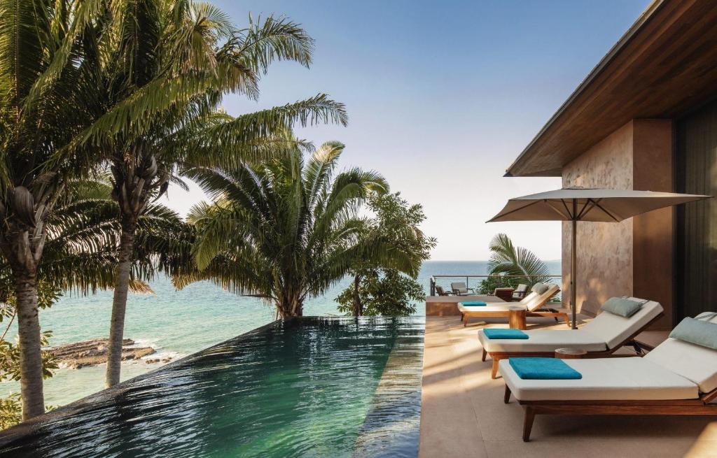 an infinity pool at a resort with palm trees and the ocean at One&Only Mandarina in Lo de Marcos