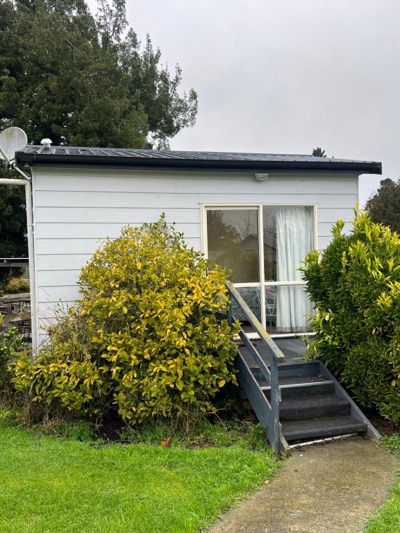 a small white house with a porch and stairs at Green Hayes Estate Rentals - Green Hayes Cabin in Temuka