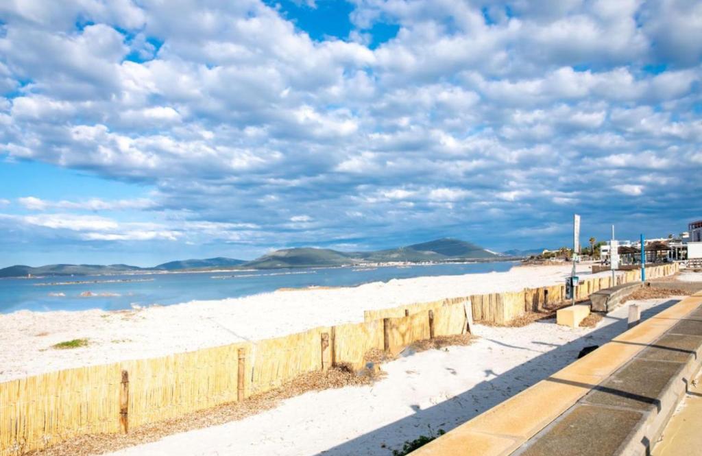 a beach with white sand and a wooden fence at La Casa di Lore & Leo in Alghero