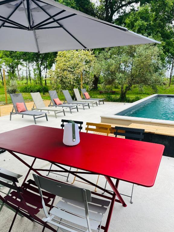 a red table and chairs next to a pool at La Casa M-maison idéale pour groupes familles amis 12 personnes au calme avec piscine in Sainte-Hélène