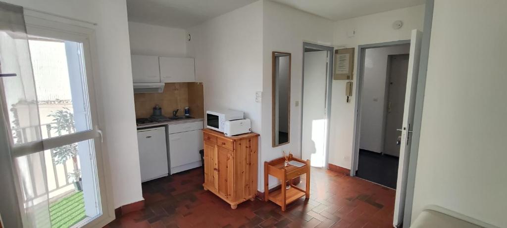 une cuisine avec des placards blancs et un four micro-ondes sur un comptoir dans l'établissement La plage, à Saint Cyprien Plage