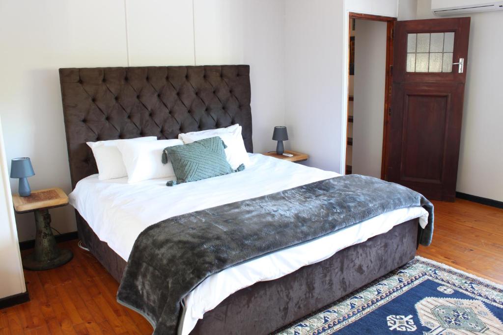 a bedroom with a large bed with a large headboard at The Old Barracks Boutique Guesthouse in Bathurst