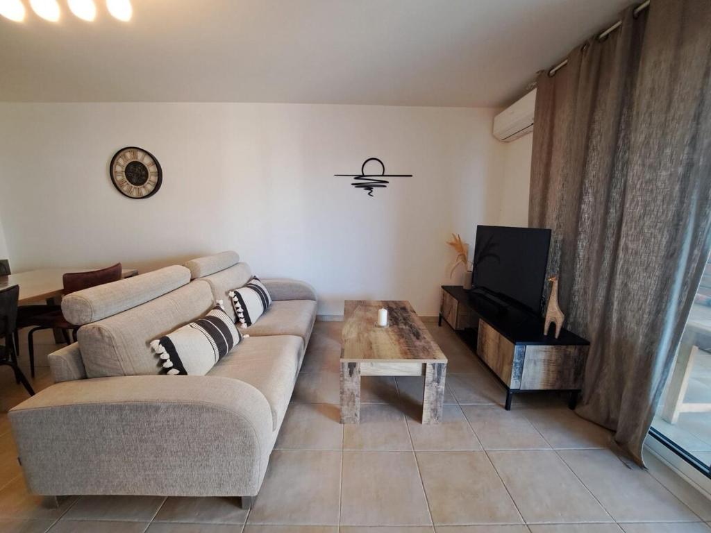 un salon avec un canapé, une table et une télévision dans l'établissement T3 proche plage, dans résidence avec piscine, à Calvi