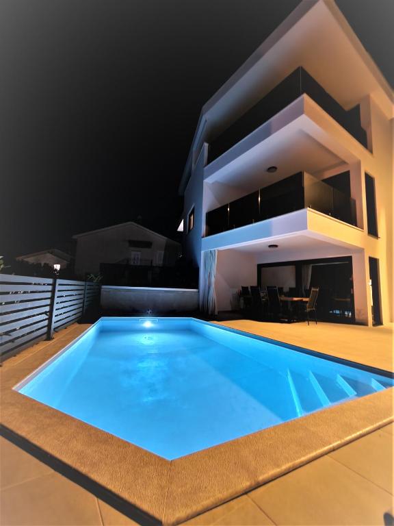 a swimming pool in front of a house at night at Luxury apartment Marco Polo with a private swimming pool with salt sea water in Punat