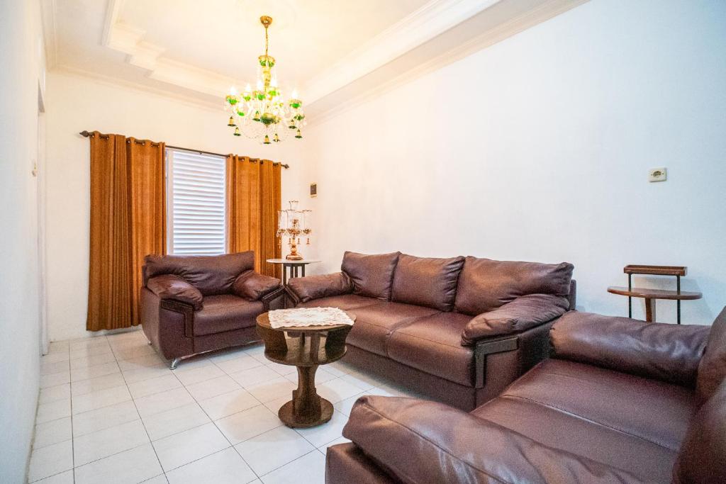 a living room with leather furniture and a chandelier at Puri 11 Homestay Jogja in Ngemplak