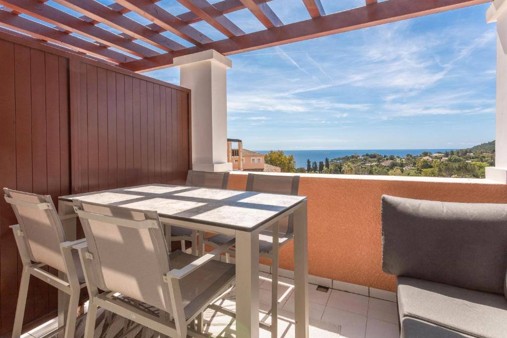 Una mesa y sillas en un balcón con vista al mar. en Appartement Cap Esterel - piscine, en Saint-Raphaël