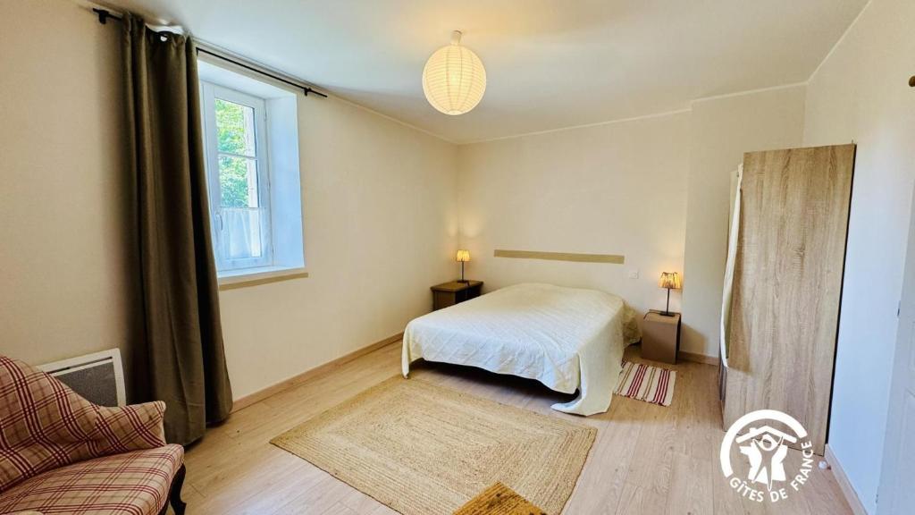 a bedroom with a bed and a couch and a window at Le cazal in Sainte-Eulalie