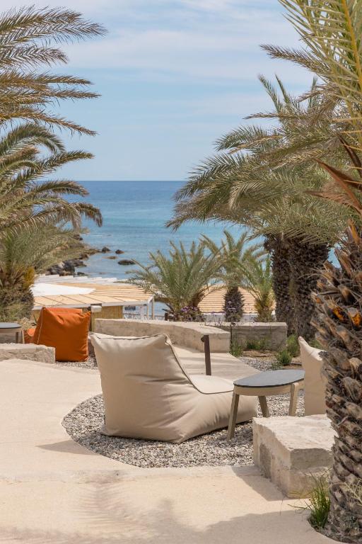 a couch on the beach with palm trees and the ocean at Golden Milos Beach Ηouse by Domotel in Provatas