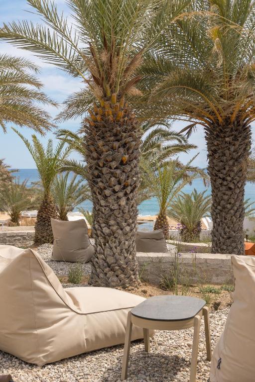 a couch and a table in front of palm trees at Golden Milos Beach Ηouse by Domotel in Provatas