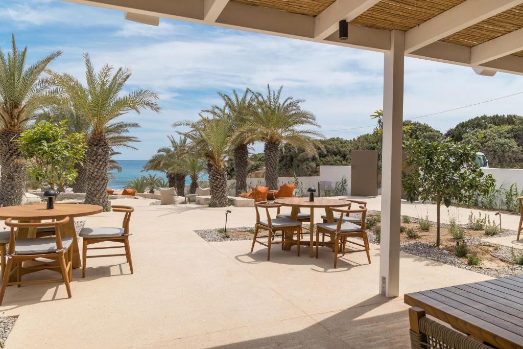 a patio with tables and chairs and the ocean at Golden Milos Beach Ηouse by Domotel in Provatas