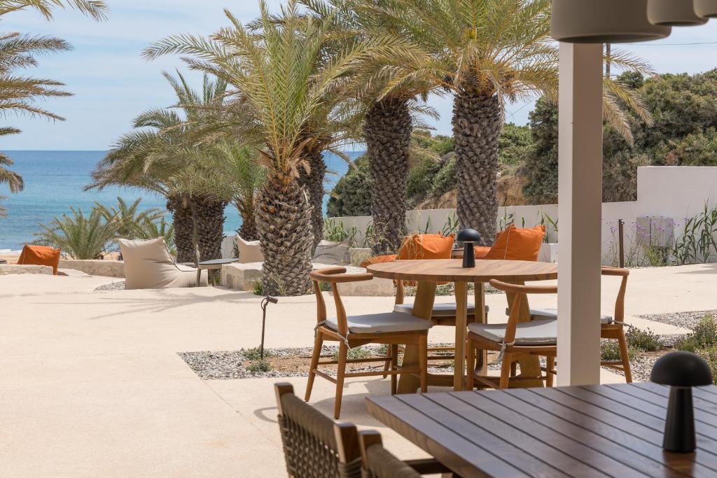 a patio with a table and chairs and palm trees at Golden Milos Beach Ηouse by Domotel in Provatas