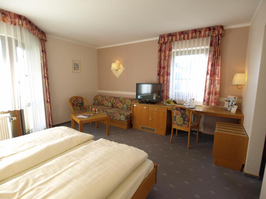 a hotel room with a bed and a couch and a desk at Hotel Landhaus Silbertanne in Rotenburg an der Fulda