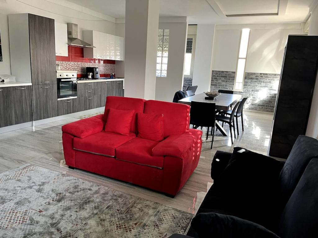a red couch in a living room with a kitchen at 'C'est la vie' Apartment VR20 in Gela