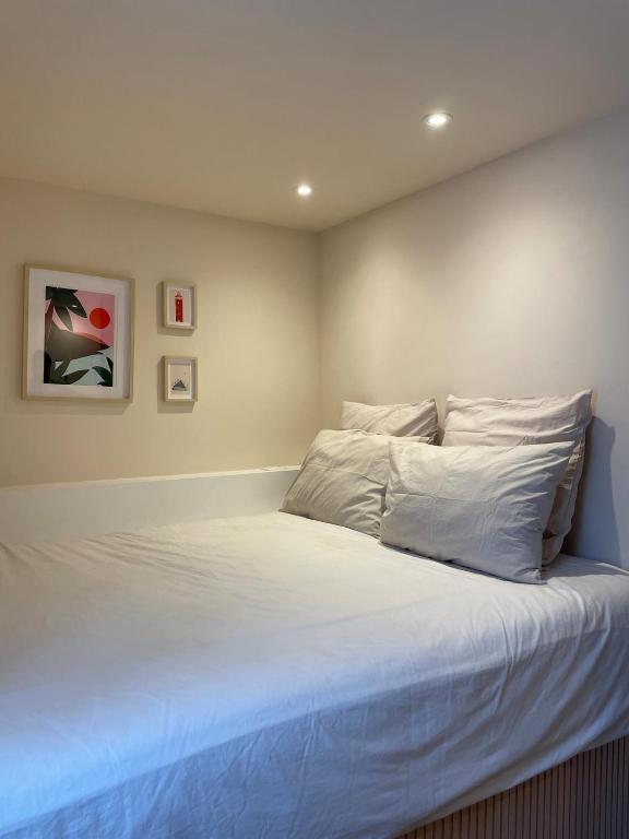 une chambre avec un lit avec des draps blancs et des oreillers dans l'établissement Charmant appartement avec terrasse à deux pas de l'océan, à Hourtin