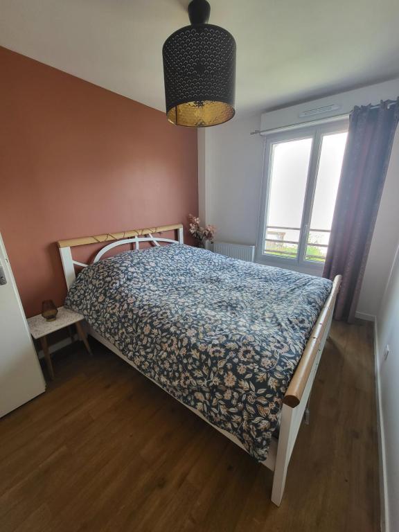 une chambre avec un lit avec une couette bleue et une fenêtre dans l'établissement Chambre chez l'habitant, au Mans