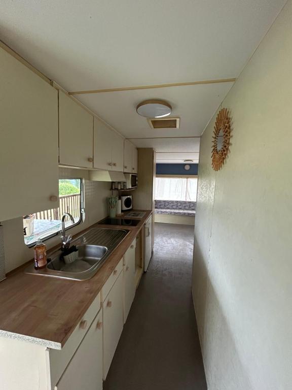 a kitchen with white cabinets and a sink and a window at Mobile Home Bleu in Fleurac