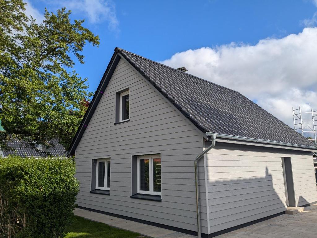 a white house with a black roof at Lütt achtern Diek in Neufeld
