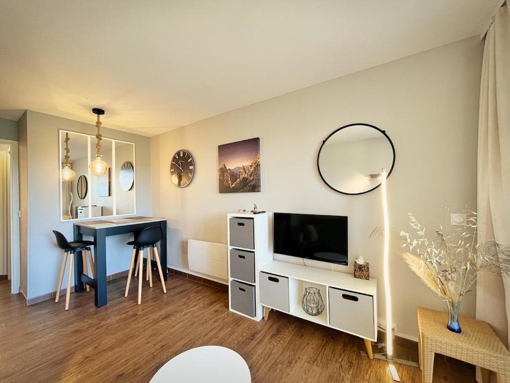 - un salon avec une table, une télévision et un bureau dans l'établissement La Perle Blanche, à Saint-Raphaël