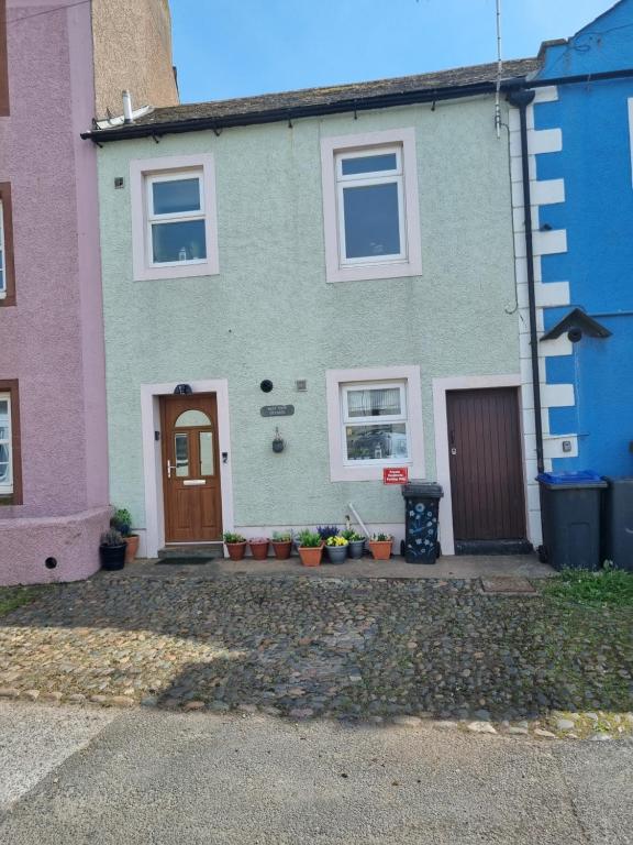 una casa verde con finestre bianche e una porta marrone di West View Cottage in Seaside Village of Allonby Cumbria ad Allonby