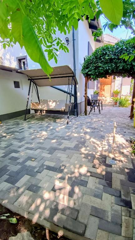 a patio with a canopy and a table and bench at Regina Vendégház Miskolc in Miskolc