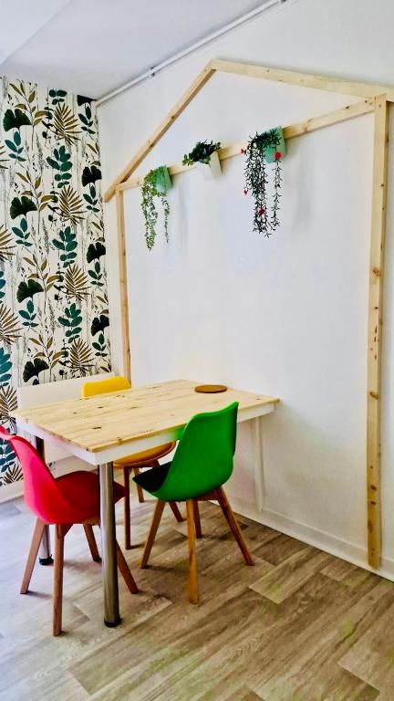 une pièce avec une table en bois et des chaises colorées dans l'établissement Le Mosaïque, à Périgueux