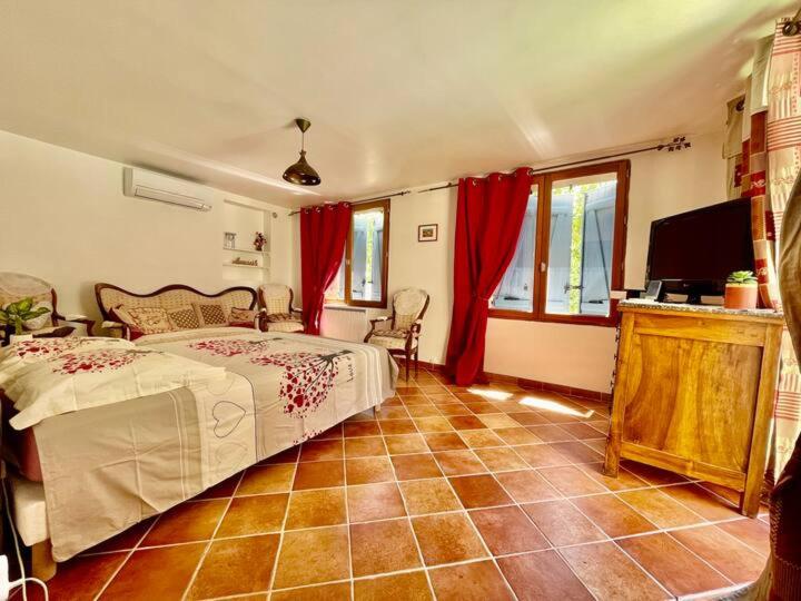 Cette chambre comprend un lit avec des rideaux rouges et une télévision. dans l'établissement La Belle de Castille, à Argilliers
