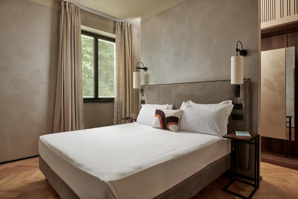 a bedroom with a large white bed with a window at Maximilian Suites in Trieste