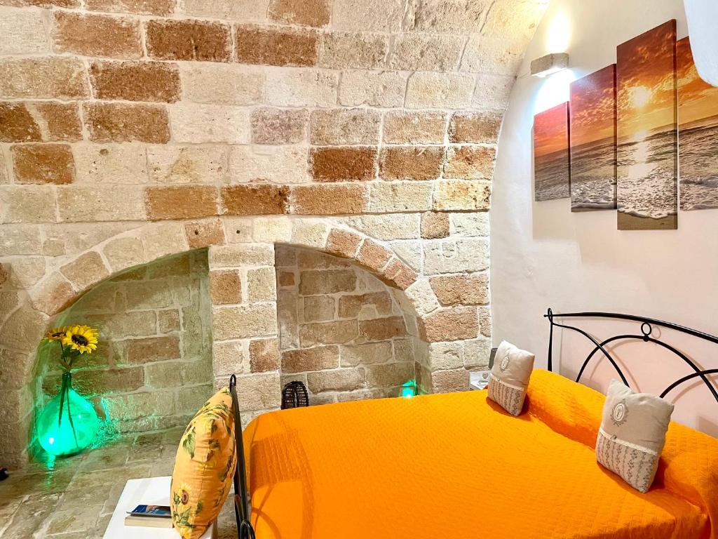 a yellow bed in a room with a brick wall at Antica Pietra in Polignano a Mare
