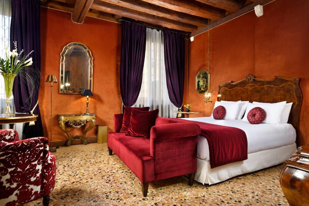 a bedroom with a large bed and a red chair at Palazzo Venart Luxury Hotel in Venice