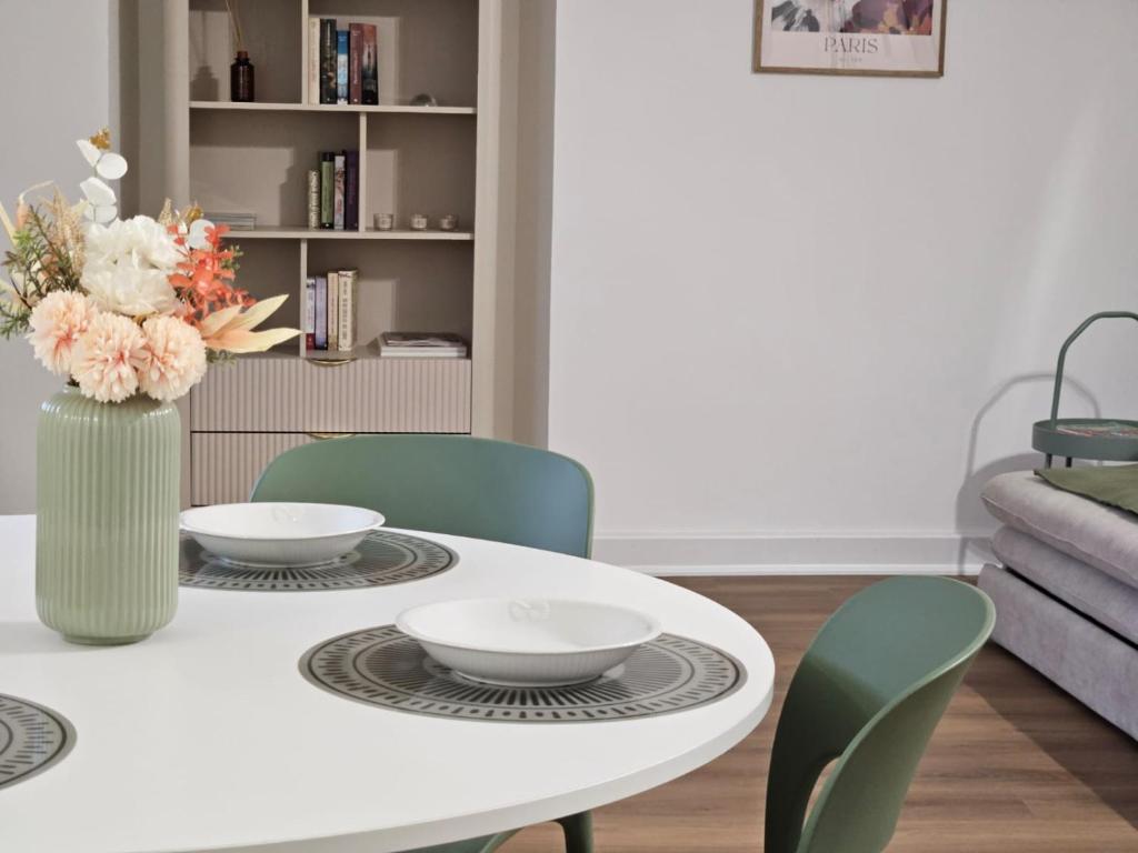 a white dining room table with chairs and a vase with flowers at Be Your Home - Olilà in Civitavecchia