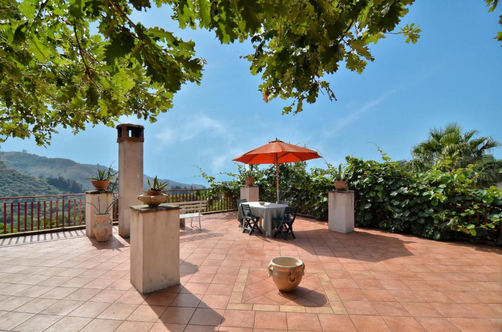 a patio with a table and an umbrella at Agriturismo Etna-Mare in Piedimonte Etneo