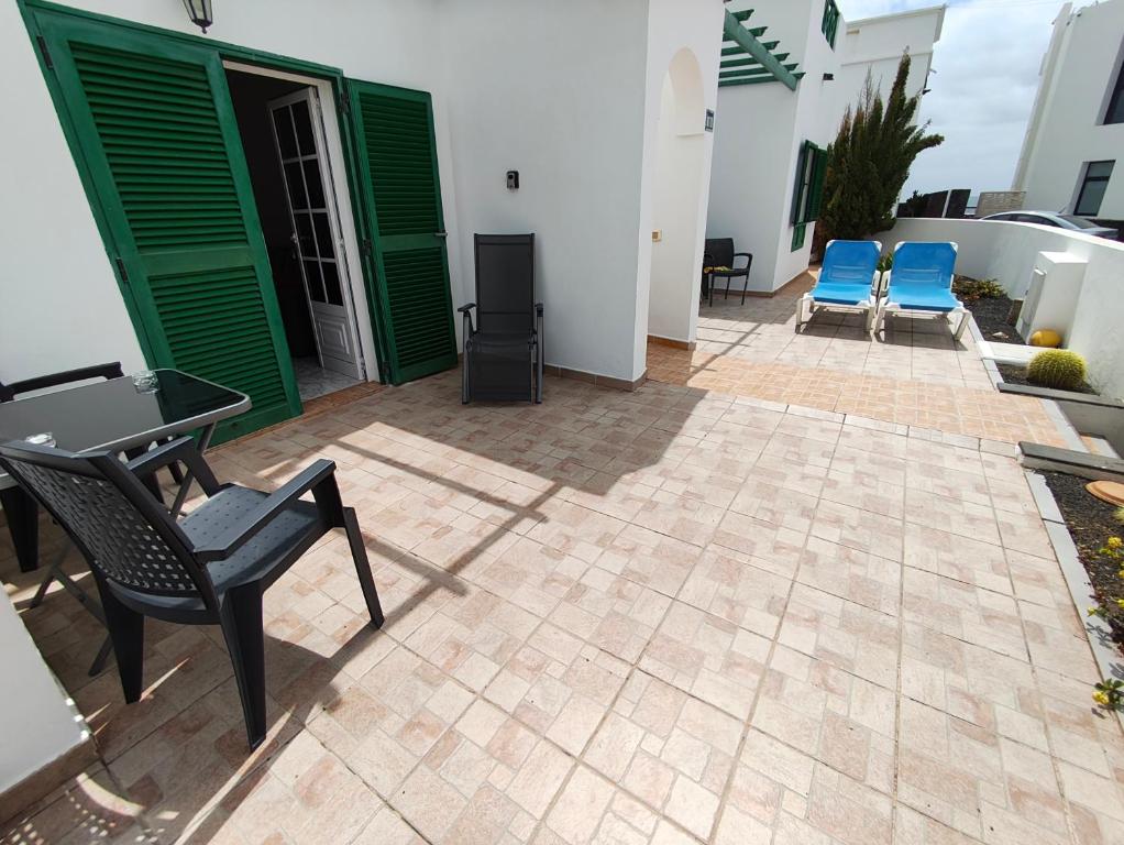 patio z 2 krzesłami i stołem oraz 2 niebieskimi krzesłami w obiekcie MarySol 1 Apartment with terrace close to the sea w mieście Punta de Mujeres