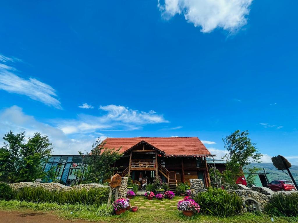 une maison avec un toit rouge et quelques fleurs dans l'établissement Săn Mây Coffee and Homestay Măng Đen, à Kon Von Kla