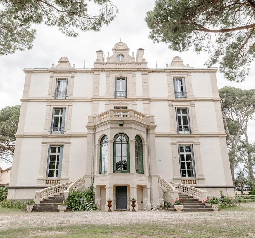 a large white house with stairs in front of it at Château de Bayssan in Béziers