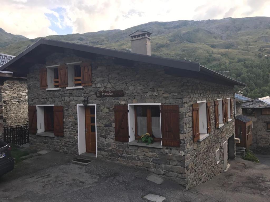 une maison en pierre avec des fenêtres et une montagne en arrière-plan dans l'établissement La Faucille 3, à Praranger
