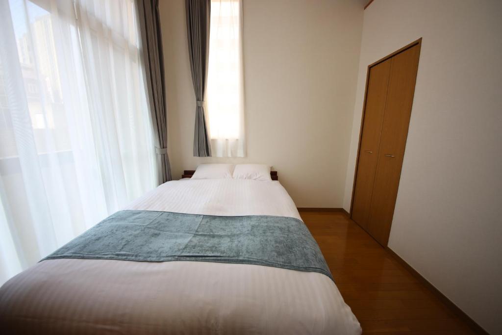 a white bed in a room with a window at goom Hotel Nakasu JOJO in Fukuoka