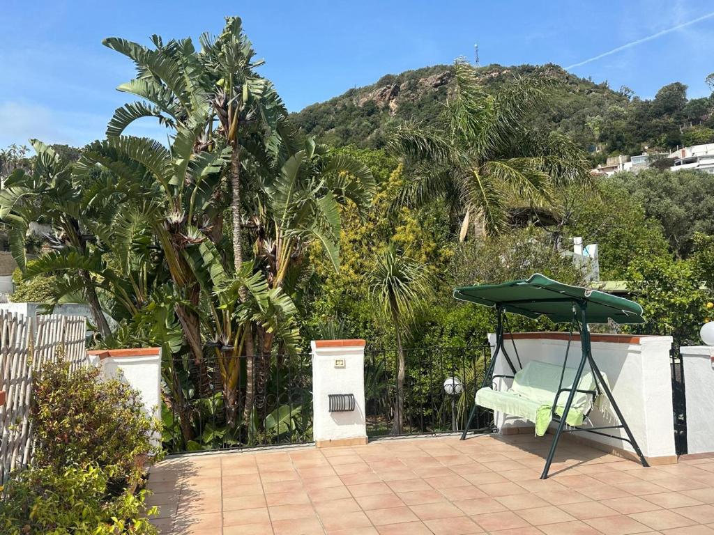 a patio with a green umbrella and a bench at Villa Robienne in Forio d'Ischia